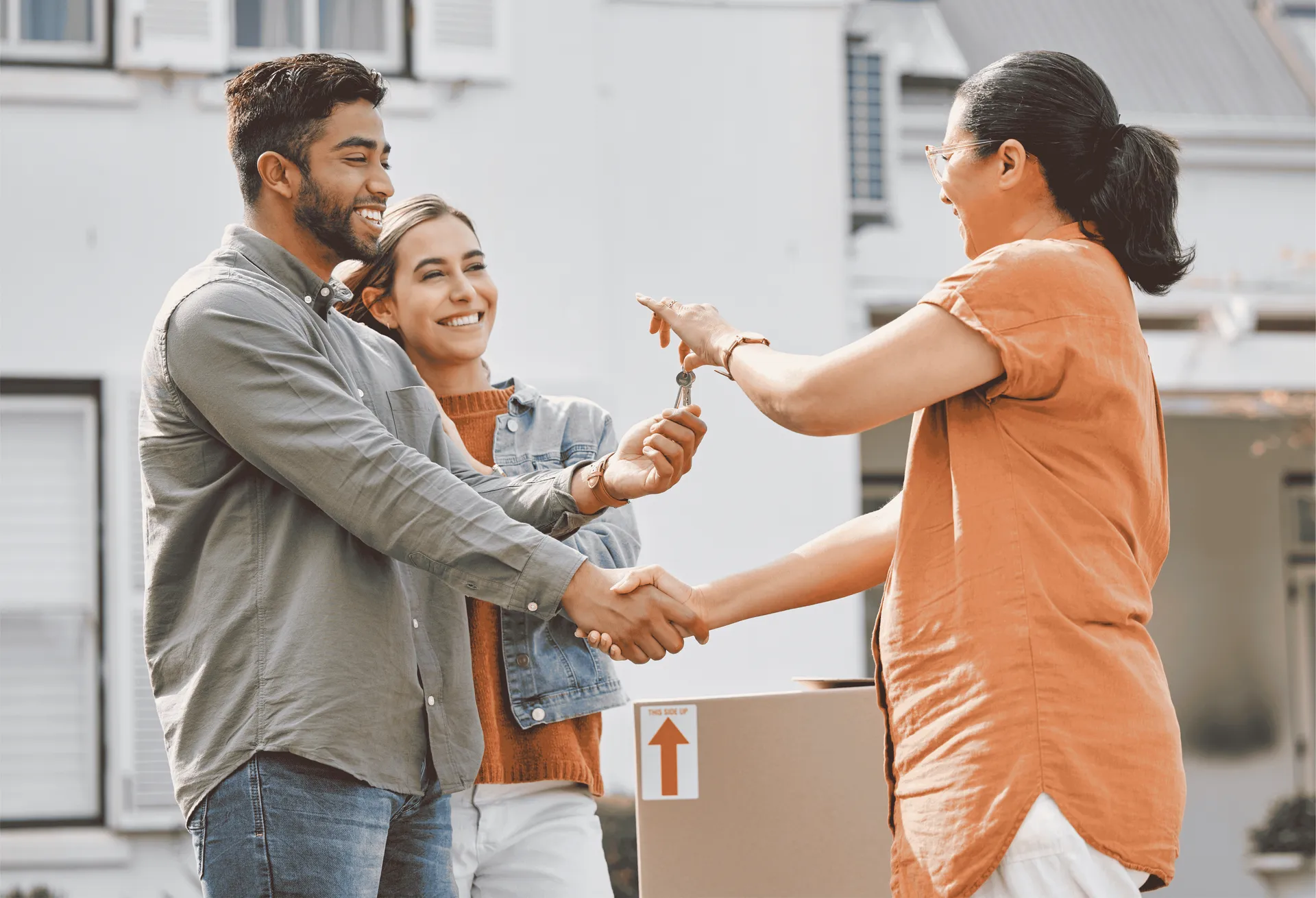 Realtor handing over keys and shaking hands with new tenants, representing a streamlined tenant selection process.
